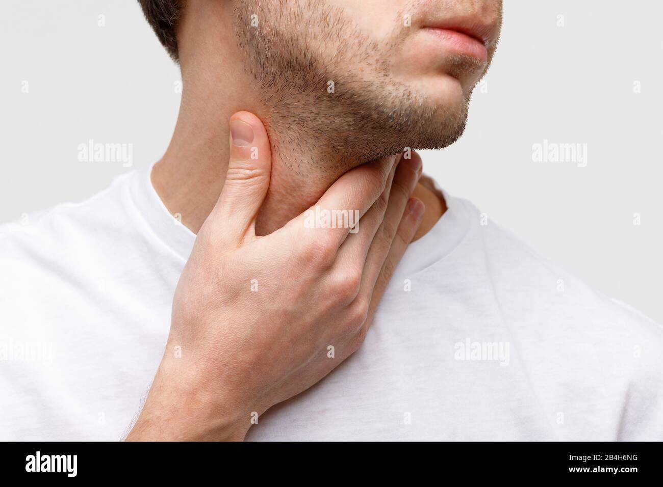 Primo piano di malato che soffre di problemi alla gola, sfondo grigio, isolato. Ghiandola tiroidea, deglutizione dolorosa, faringite, gonfiore laringeo con Foto Stock