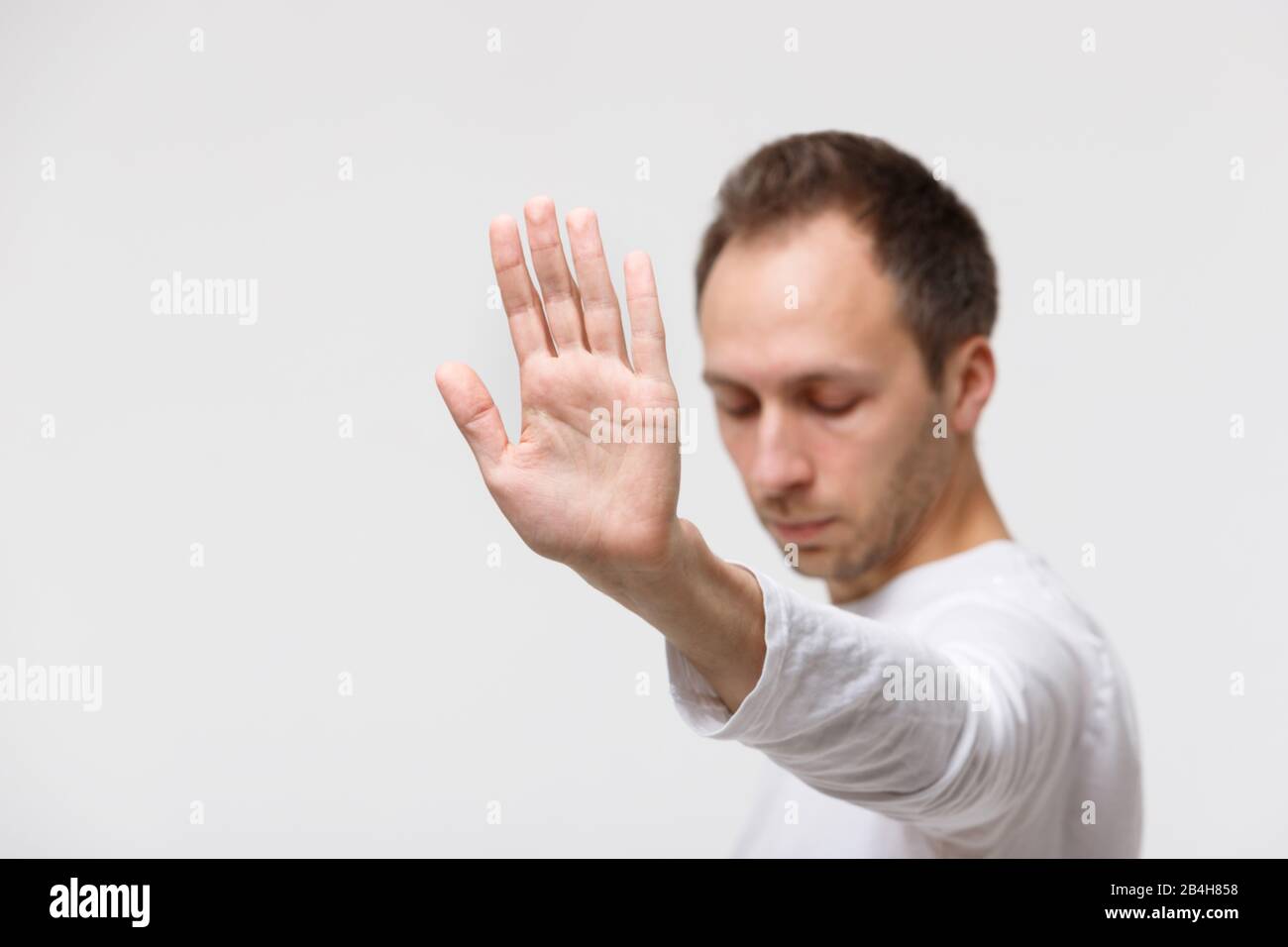 Primo piano di un uomo arrabbiato rifiuta l'offerta, mostrando un gesto di rifiutare cibo spazzatura, rifiuta qualcosa di sgradevole, fuoco selettivo. Emozione negativa, mano g Foto Stock
