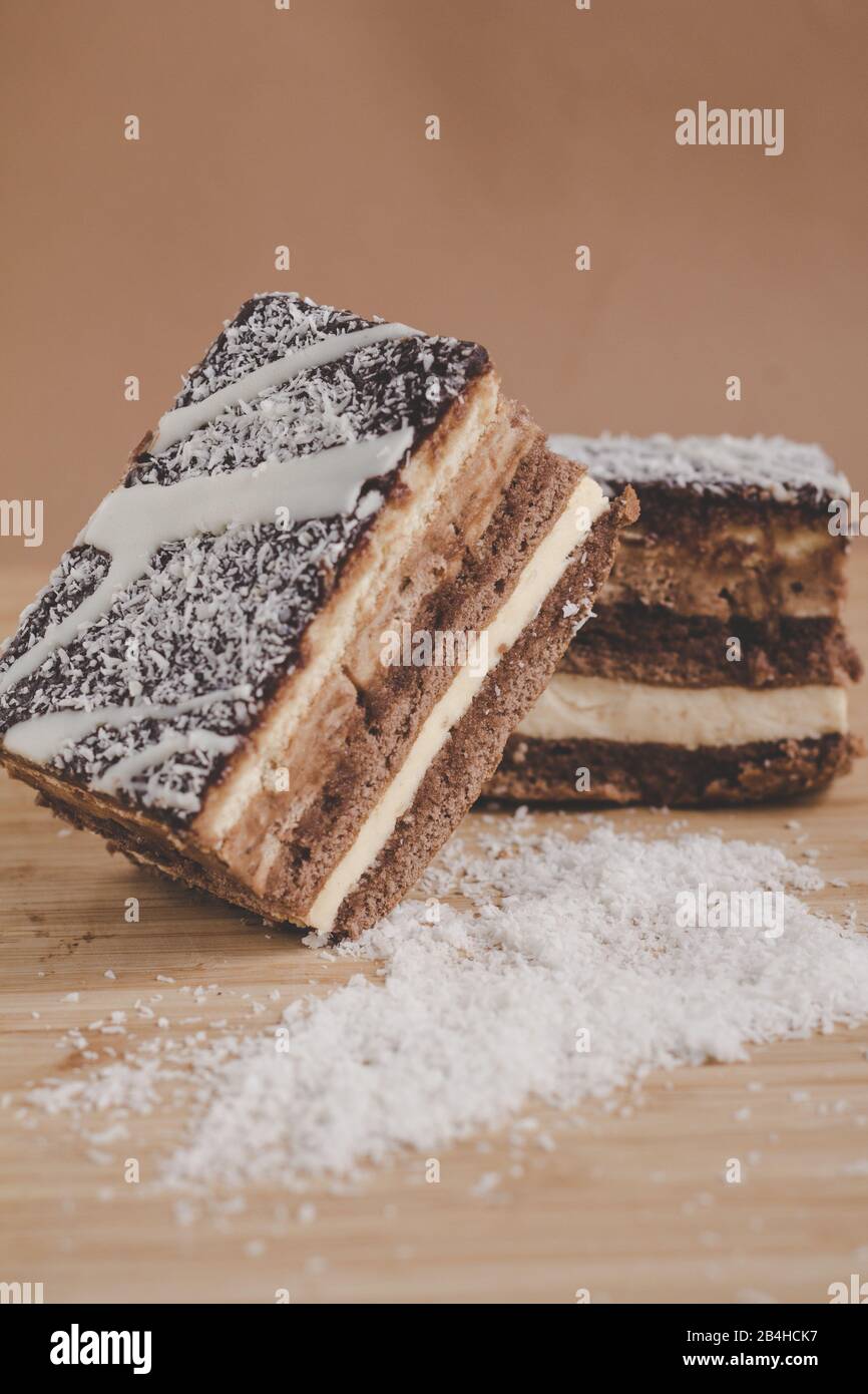 Due pezzi di torta al cocco con strati di cioccolato con fondo marrone Foto Stock