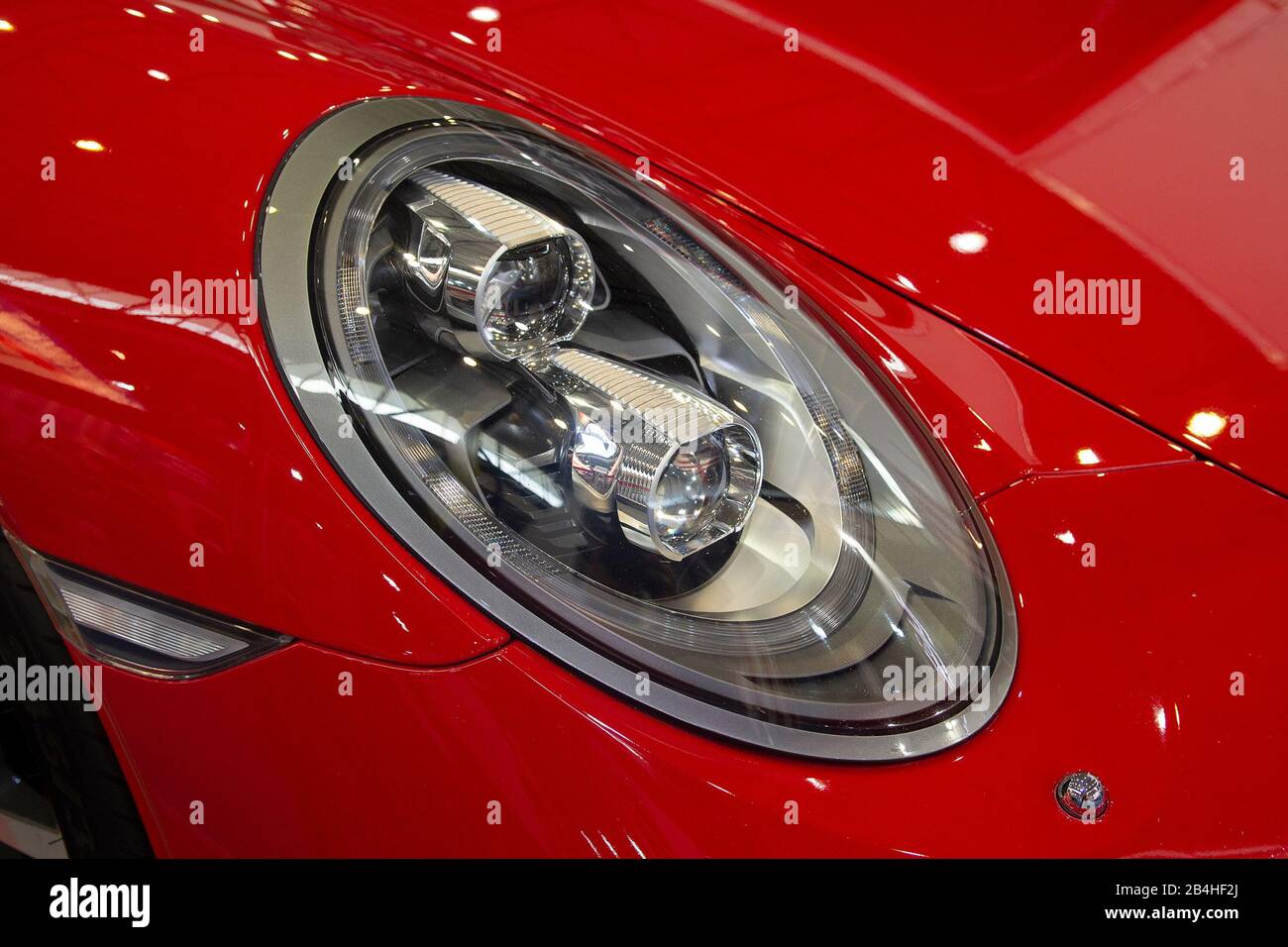 Primo piano con un faro su sfondo rosso di lusso per auto. Foto Stock