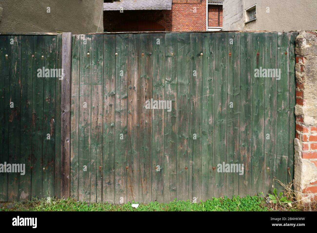 Un vecchio recinto in legno con vernice sbiadita e rusty cerniere. Foto Stock