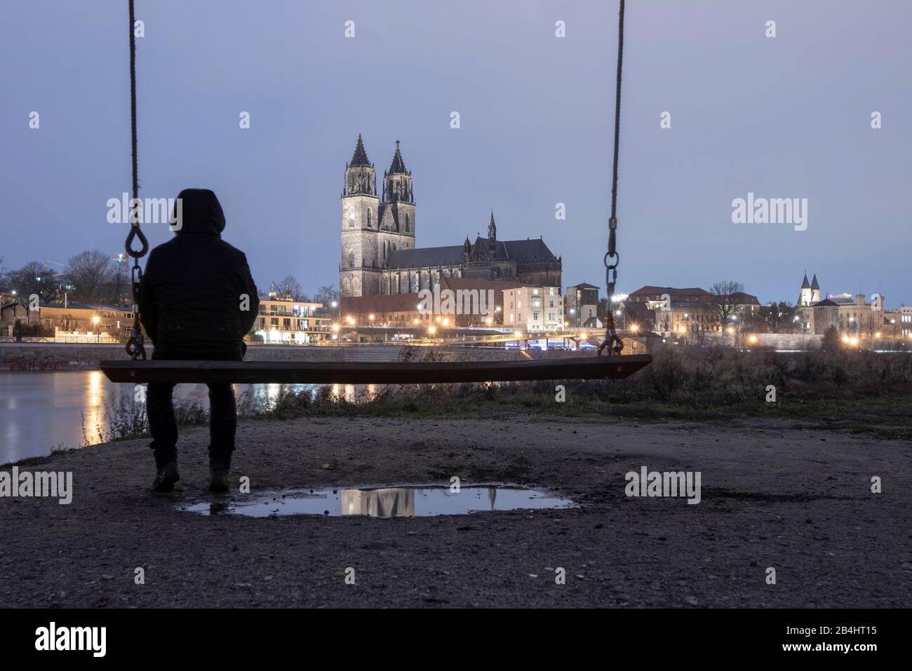 Germania, Sassonia-Anhalt, Magdeburgo, uomo seduto su swing, Cattedrale di Magdeburgo, fiume Elba. Foto Stock