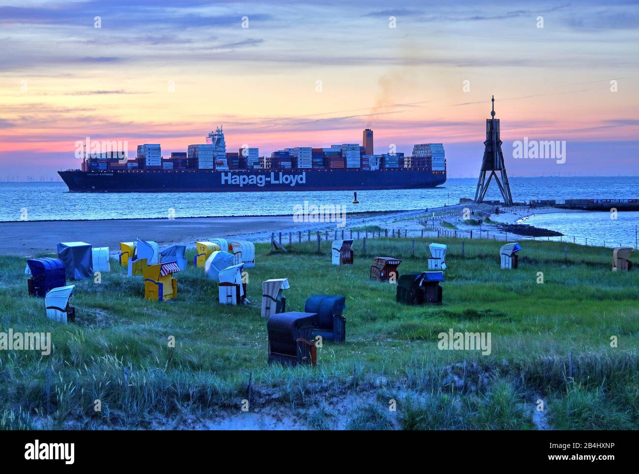 Spiaggia di erba con sedie da spiaggia Seezeichen Kugelbake e nave contenitore all'estuario dell'Elba nel quartiere Döse, località del Mare del Nord Cuxhaven, estuario dell'Elba, Mare del Nord, costa del Mare del Nord, Bassa Sassonia, Germania Foto Stock
