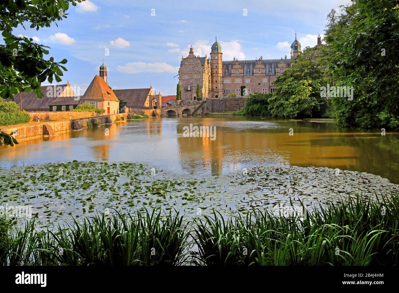 Wasserschloss Hämelschenburg con stagno castello e chiesa castello a Abendsonne, Hämelschenburg, Emmertal, Weserbergland, Bassa Sassonia, Germania Foto Stock