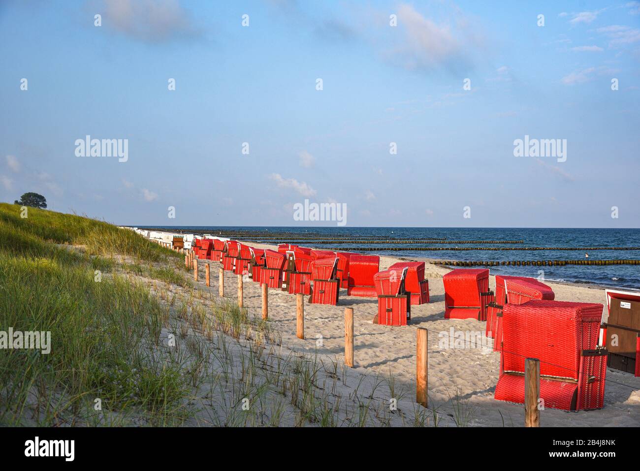 Blick über die Düne und den menschenleeren Strand mit roten Strandkörben am frühen Morgen auf dem Darß Foto Stock