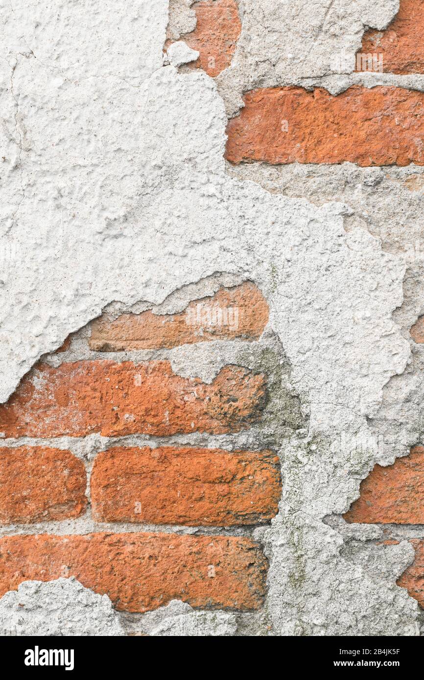 peeling muro di cemento dove si possono vedere mattoni pieni. Foto Stock