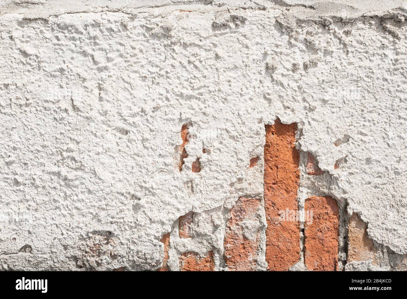 peeling muro di cemento dove si possono vedere mattoni pieni. Foto Stock