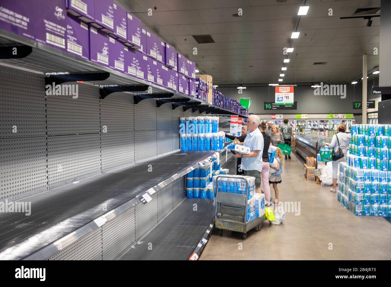 Il coronavirus in Australia conduce all'acquisto di massa di panic dei rotoli della toletta, l'uomo che compra alcuni dei pochi rotoli restanti della toletta in woolworths Foto Stock