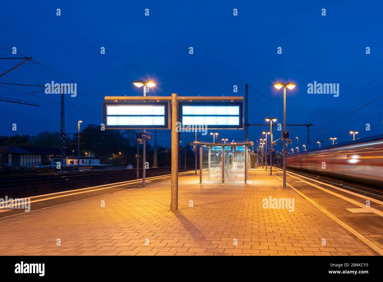 Germania, Sassonia-Anhalt, Magdeburg, piattaforma vuota, treno che entra, mattina presto, ora blu. Foto Stock