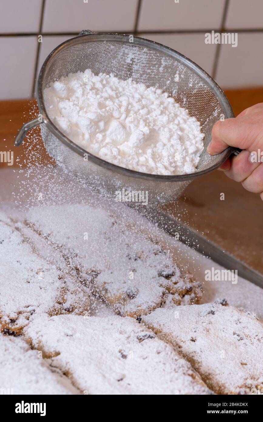 Baker strews zucchero in polvere sul Natale stollen. Foto Stock