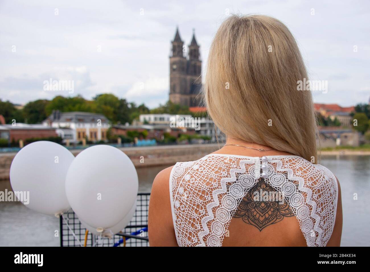 Junge Frau, biondo Haare, schaut bei einem Diner en Blanc auf den Dom a Magdeburg, trägt auf dem Rücken ein Tattoo. Foto Stock