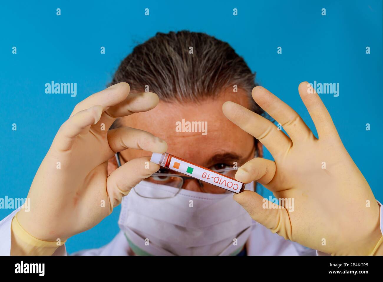 Mano di un medico che contiene una bottiglia di campione di sangue di coronavirus COVID-19 Foto Stock