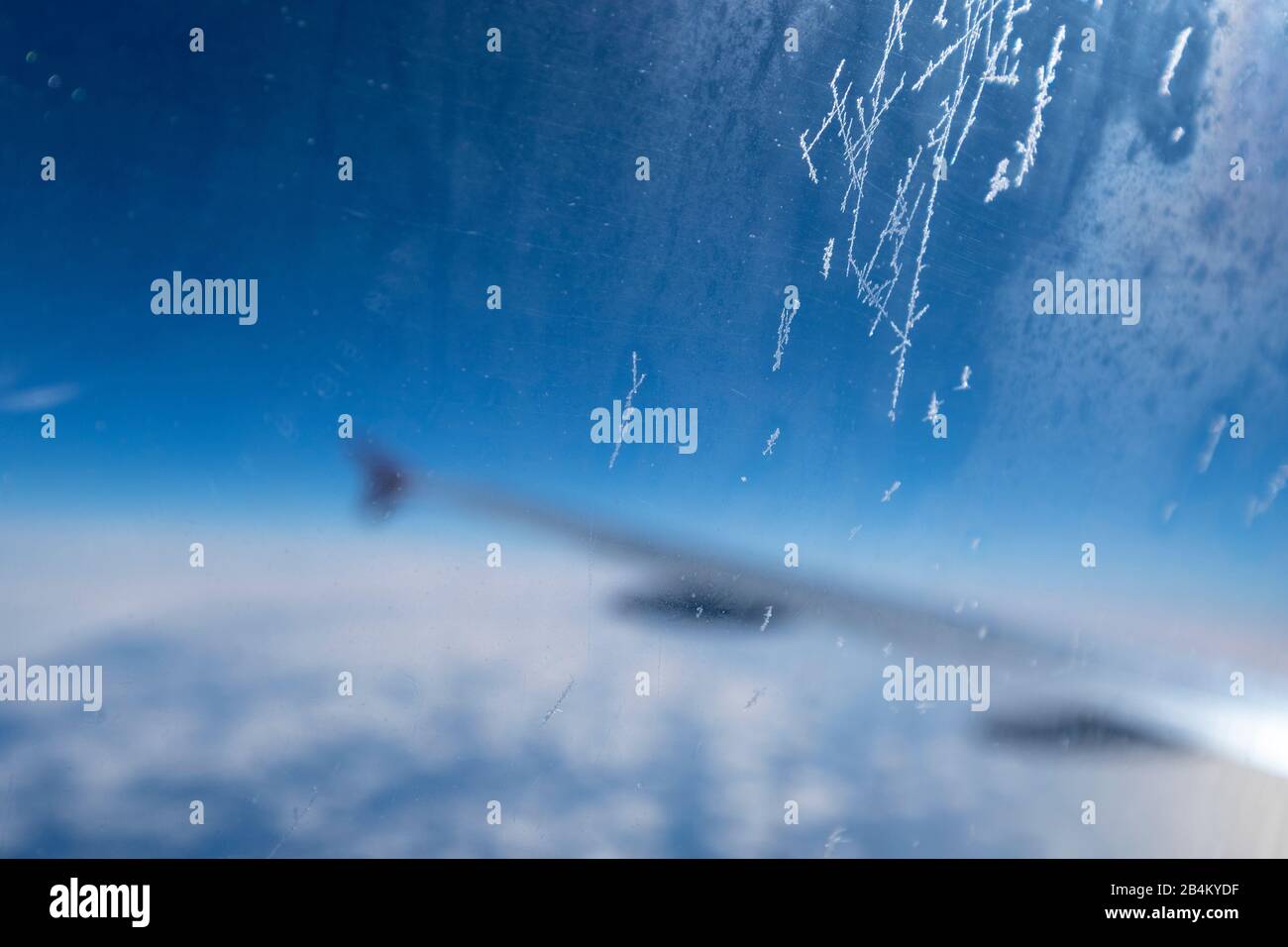 Eiskristalle am Flugzeugfenster vor blauem Himmel Foto Stock
