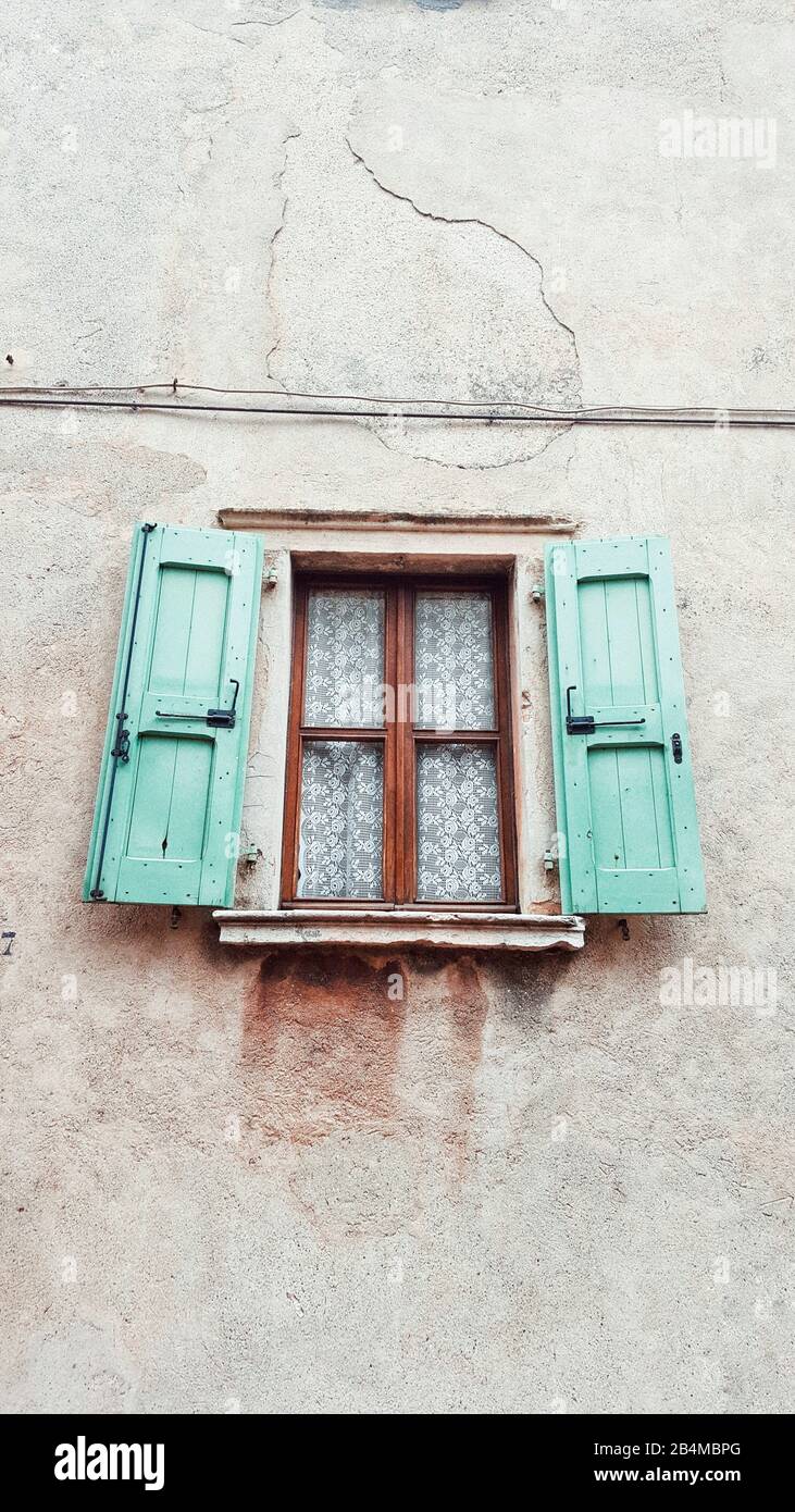 vecchia finestra con tende in vecchio stile e persiane turchesi aperte Foto Stock