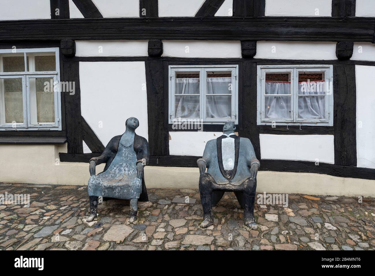 Germania, Bassa Sassonia, Harz, Goslar, casa a graticcio con due sedili in legno che simboleggiano una donna e un uomo. Foto Stock