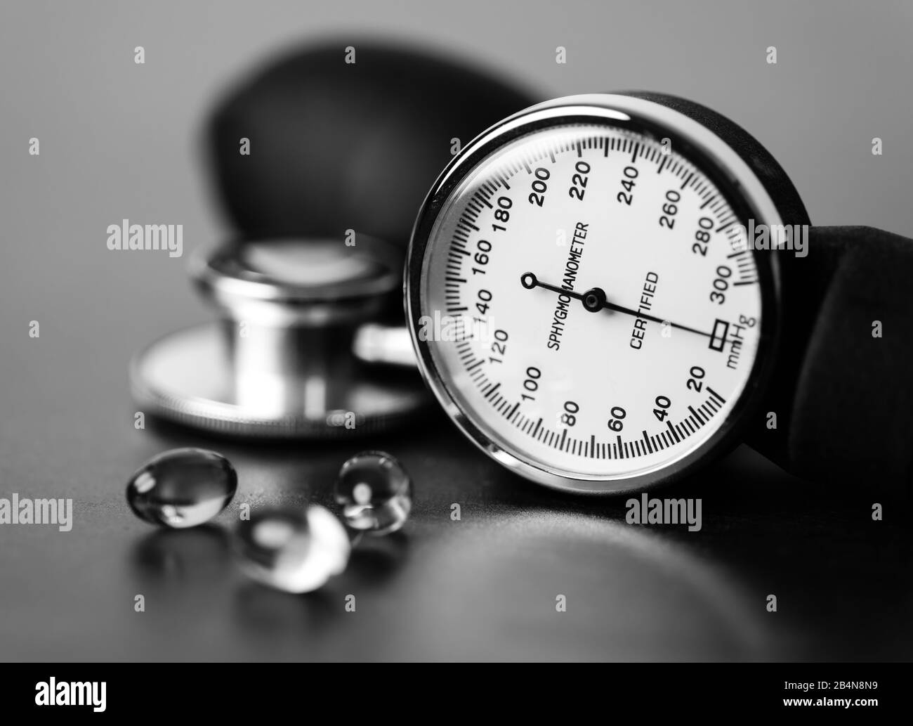 Salute e pressione sanguigna. Capsule Omega-3 che si siedono accanto al calibro di uno sfigmomanometro e alla testa di uno stetoscopio. Foto Stock