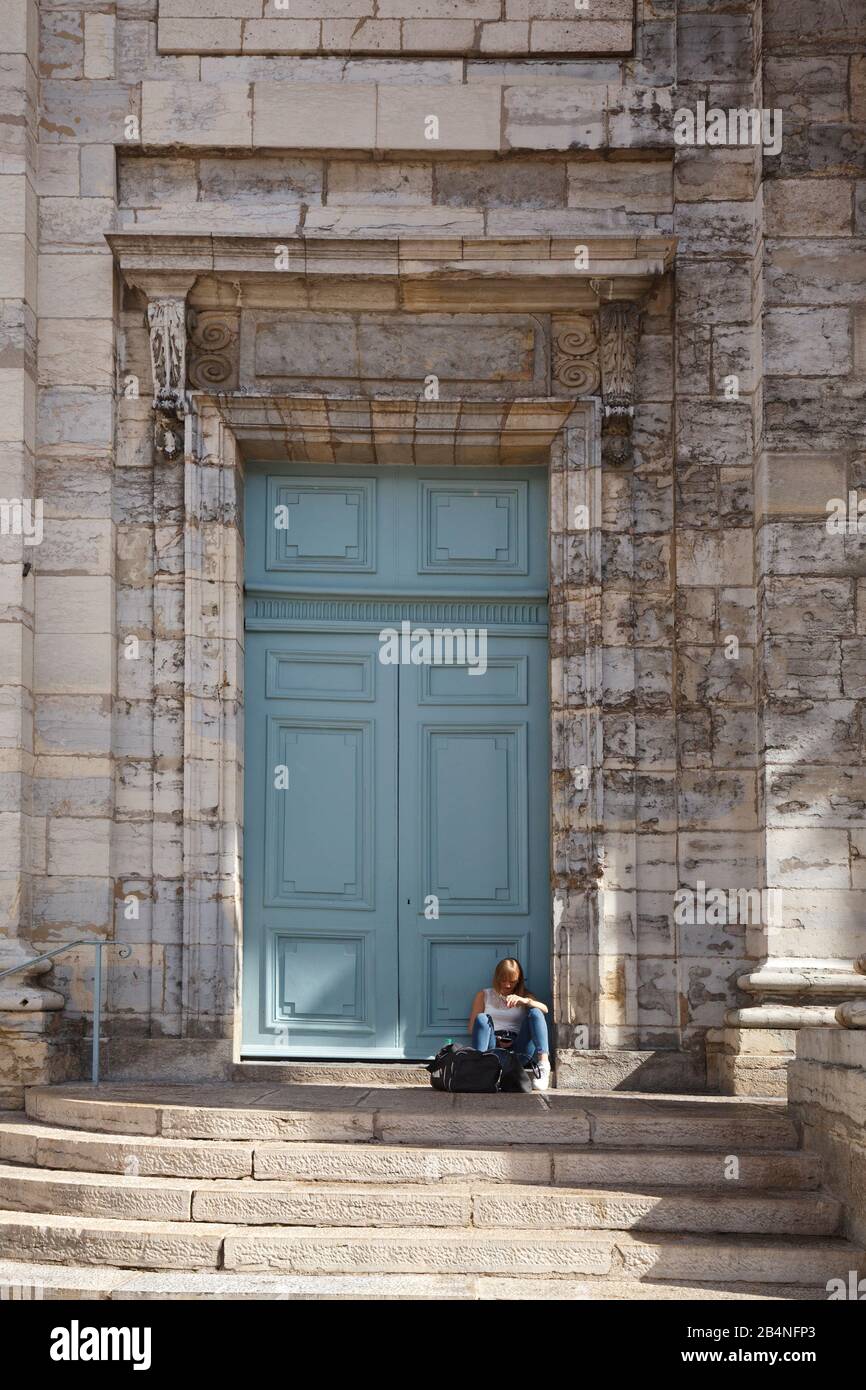 Giovane donna con cellulare si trova a piano di fronte al portale della chiesa di Saint-Pierre. Besançon è una città della Francia orientale. Dipartimento del Doubs. Foto Stock