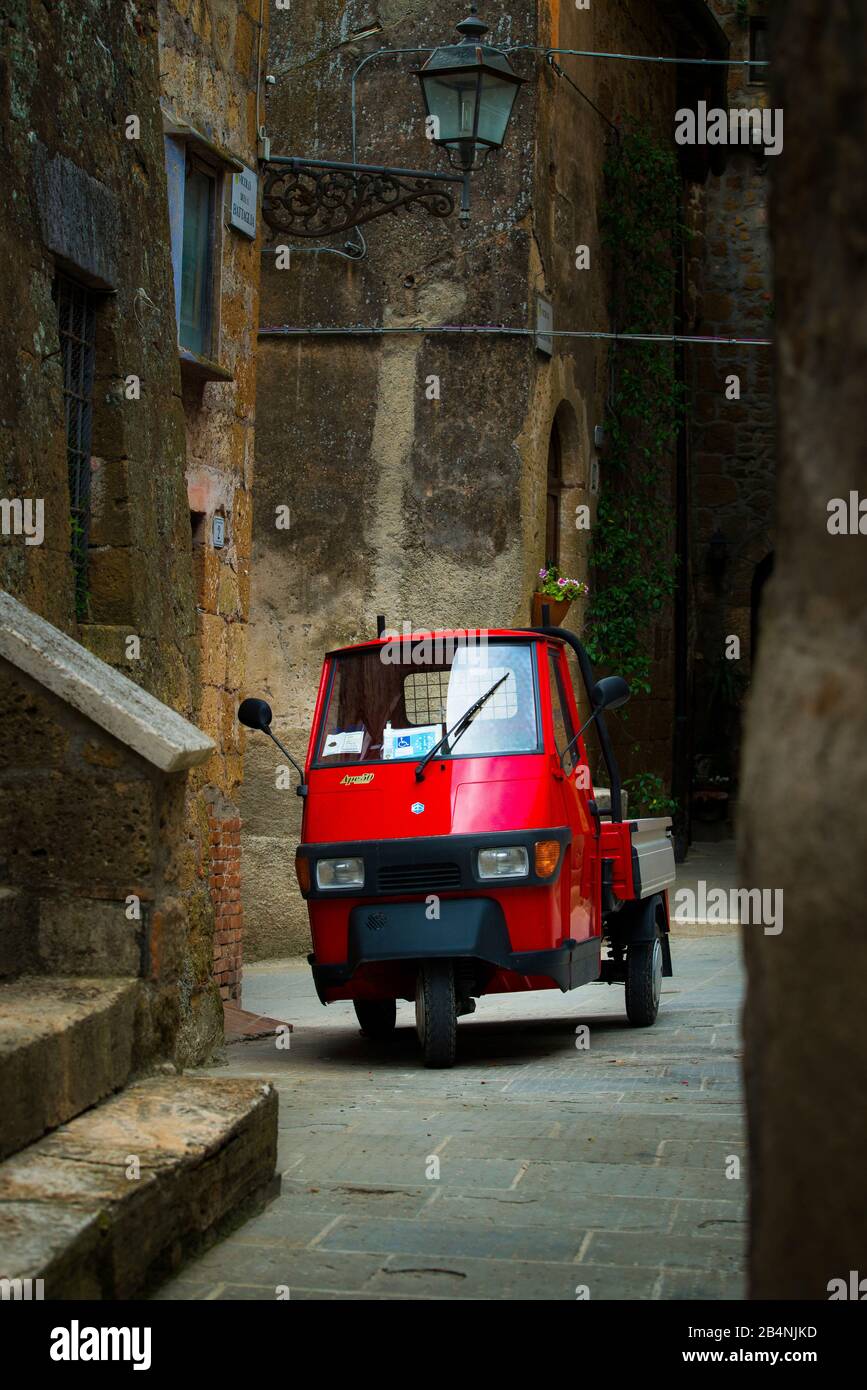 Pitigliano, Toscana, Italia, piccola auto rossa in un vicolo del centro storico Foto Stock
