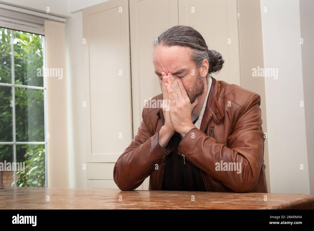 Un uomo con un ponytail che osserva lo sforzo e incerto Foto Stock