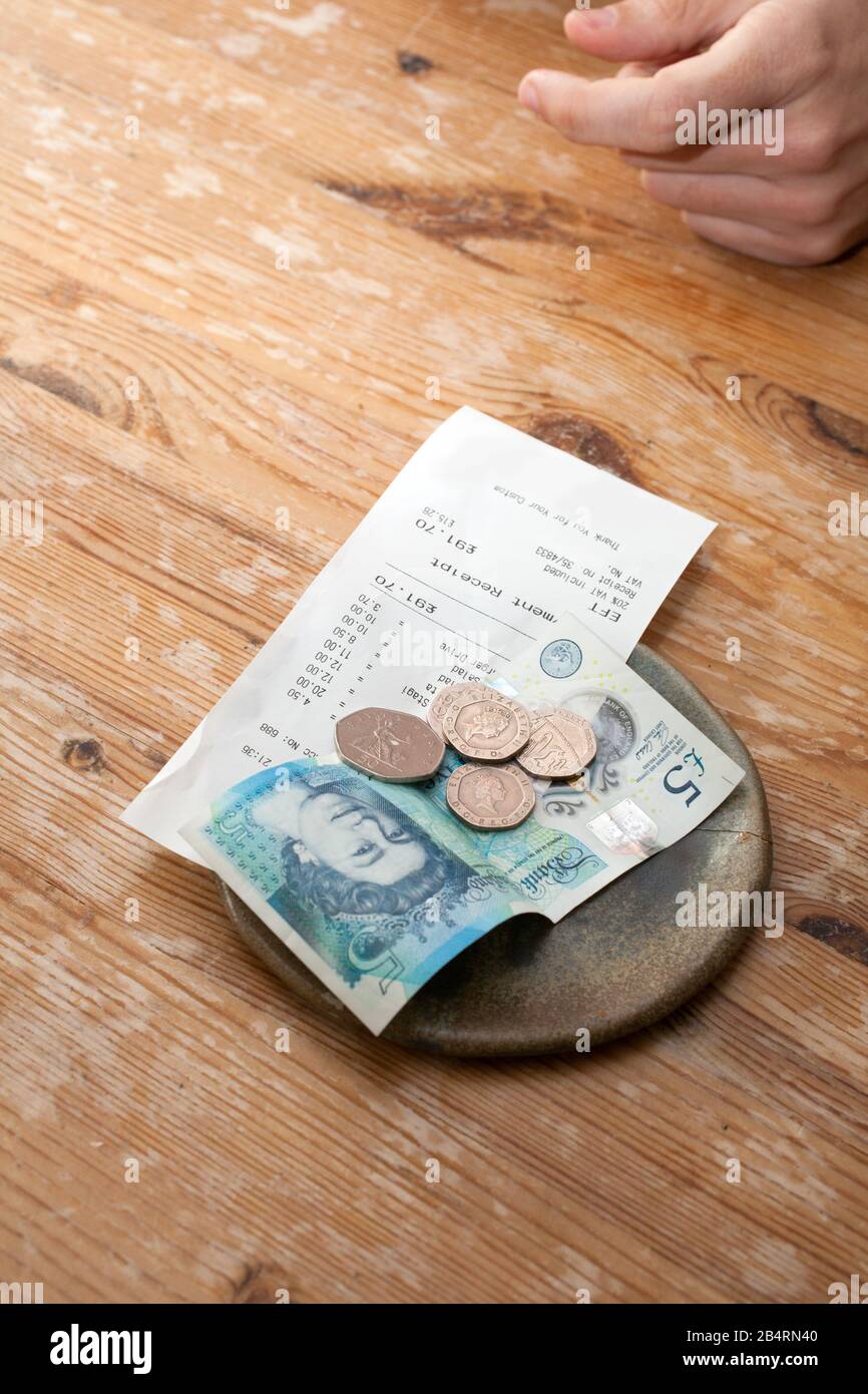 Un conto e una mancia lasciarono su un tavolo in un ristorante con soldi inglesi Foto Stock