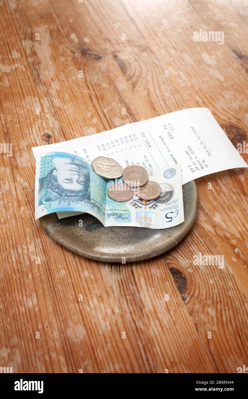 Un conto e una mancia lasciarono su un tavolo in un ristorante con soldi inglesi Foto Stock