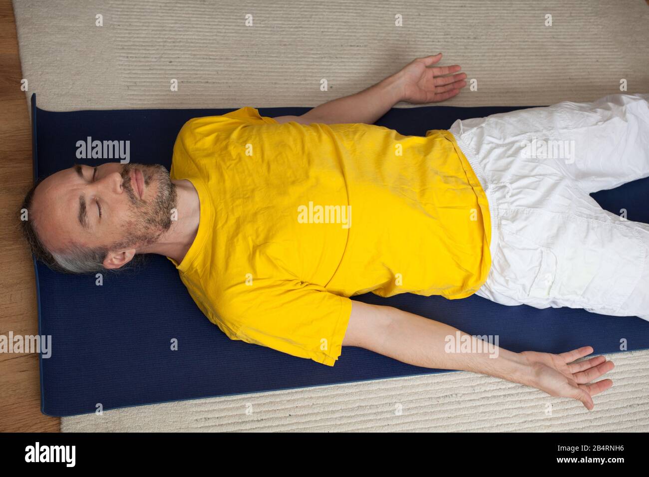 Un uomo che pratica lo Yoga a casa Foto Stock