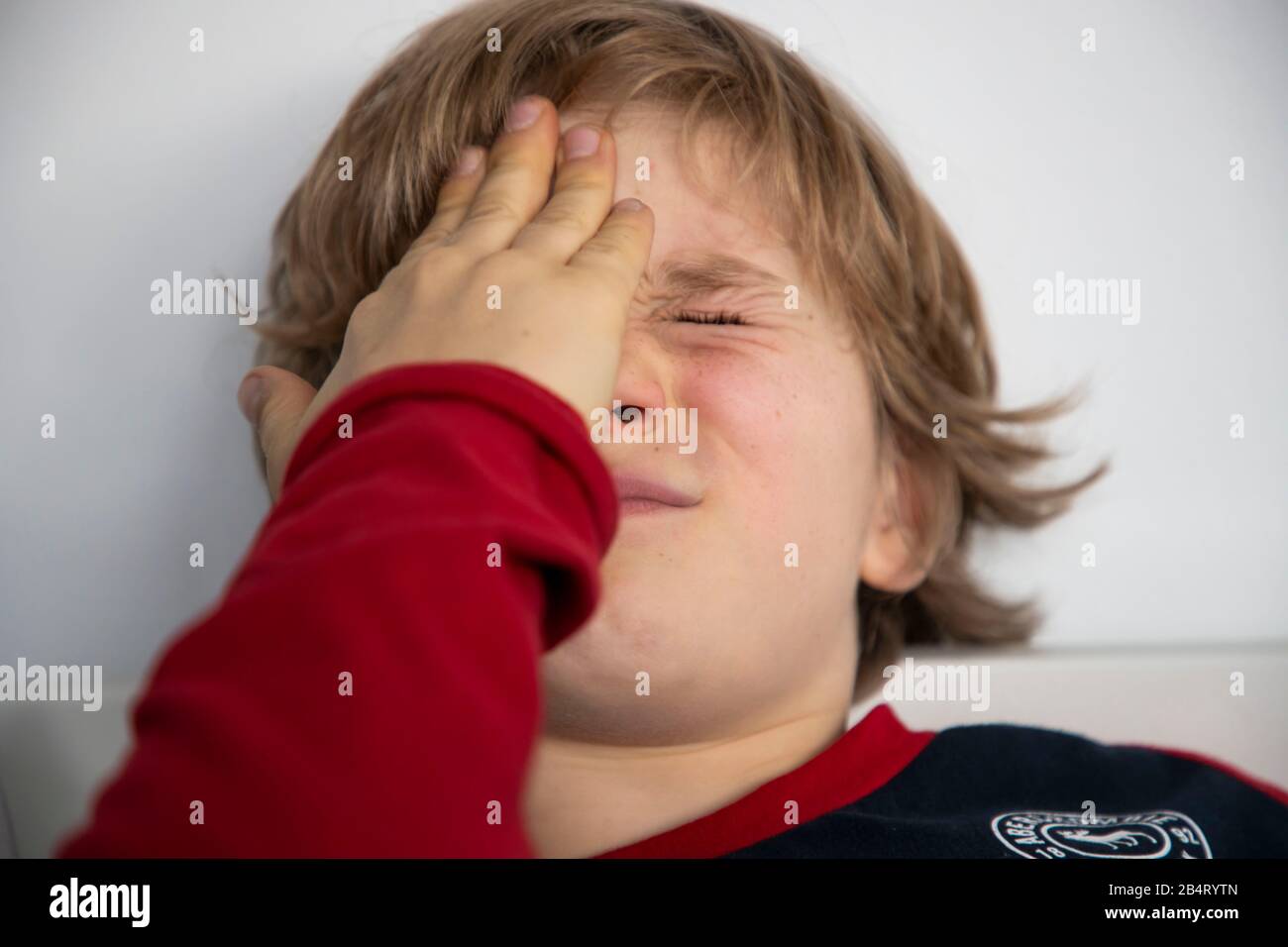 Bambino con mal di testa, ragazzo di 9 anni, con dolore viso distorto, immagine simbolica, Foto Stock