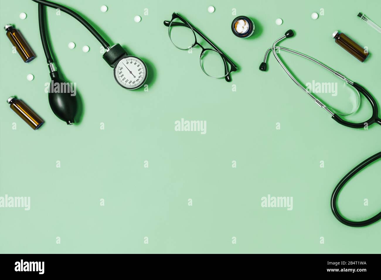 Fondo verde menta per uso medico con diversi accessori: Stetoscopio, termometro, siringa e compresse. Foto Stock