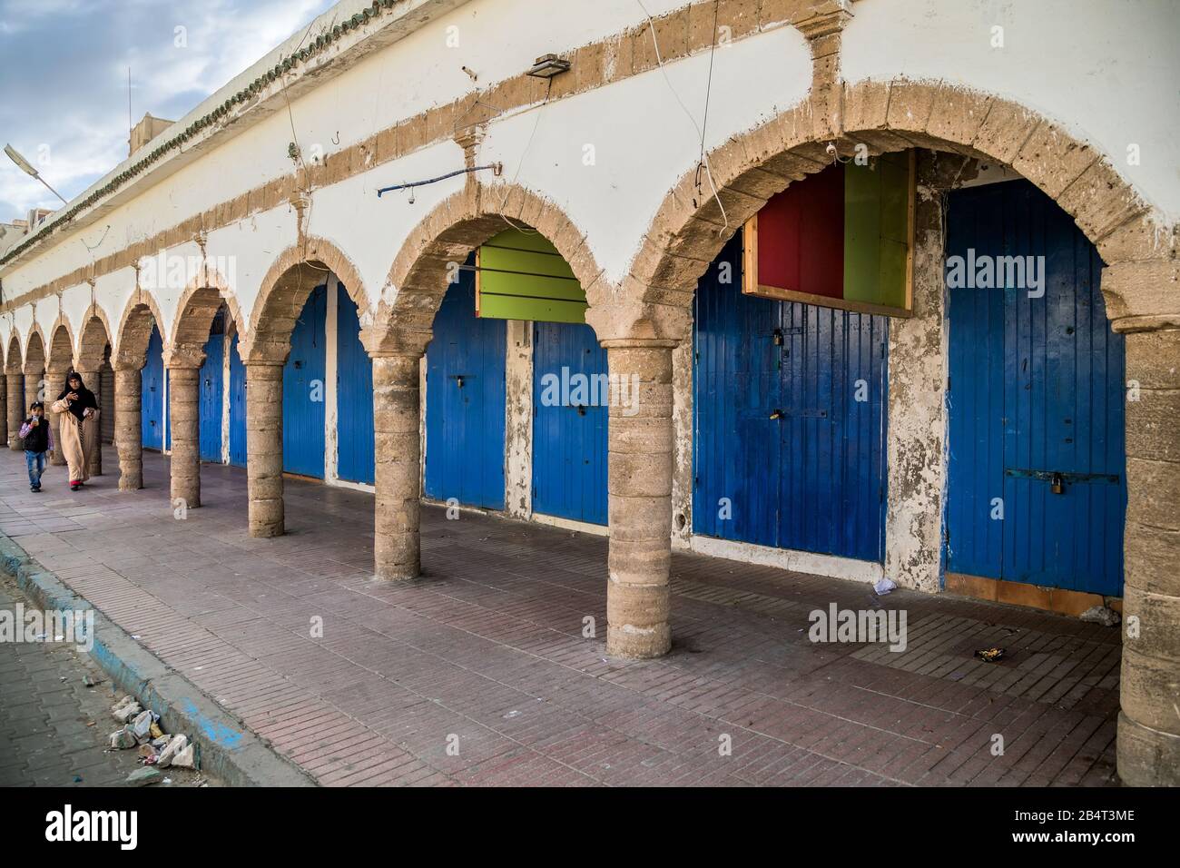 Vicolo a Essaouria Medina con negozi tradizionali dipinti di blu porta sotto i portici. La città è stata registrata come un sito Patrimonio dell'Umanità dell'UNESCO. Foto Stock