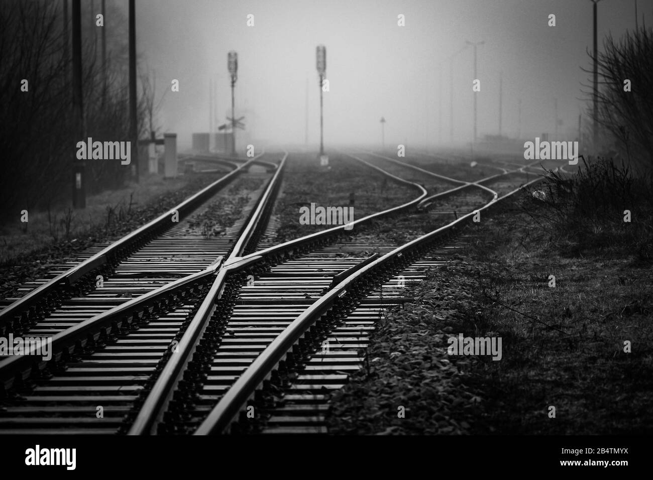 Giunzione ferroviaria con interruttori di pista che scompaiono in nebbia - immagine monocromatica Foto Stock