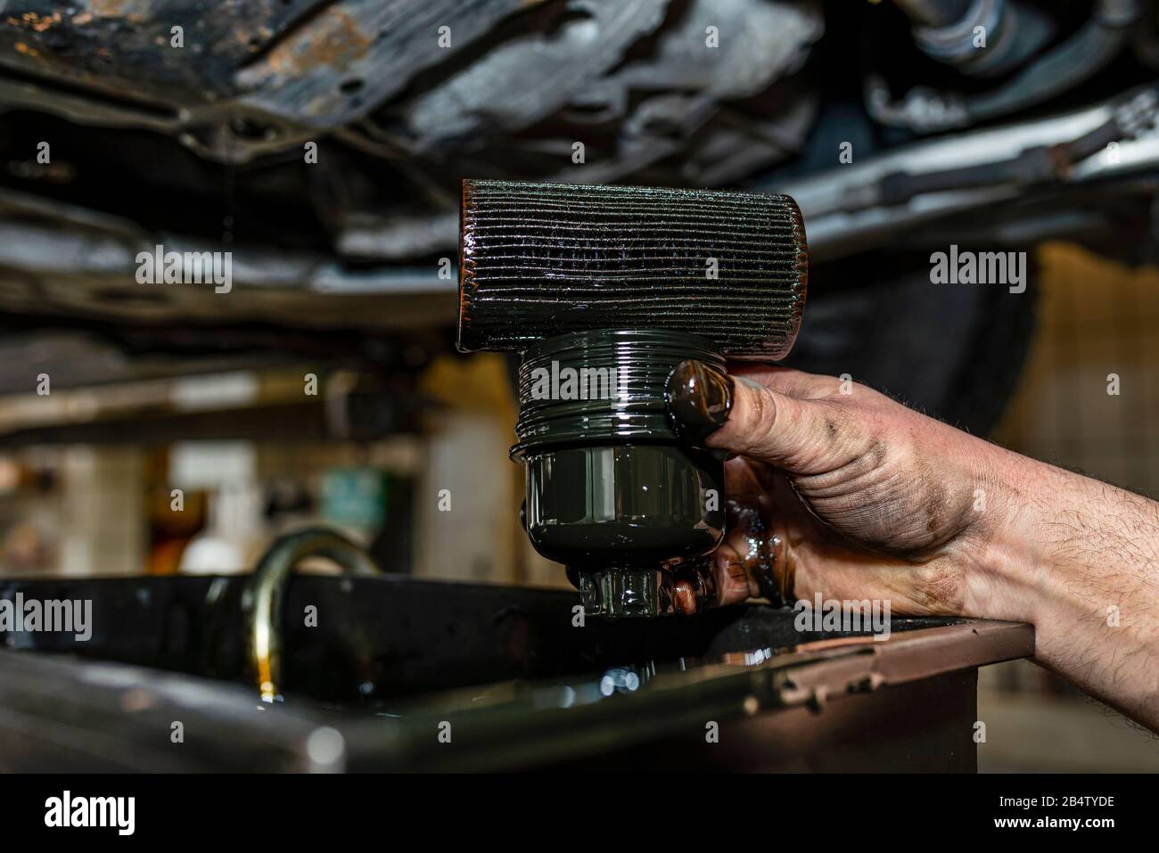 Il meccanico dell'automobile tiene il vecchio filtro dell'olio usato, sporco  con l'olio nero Foto stock - Alamy