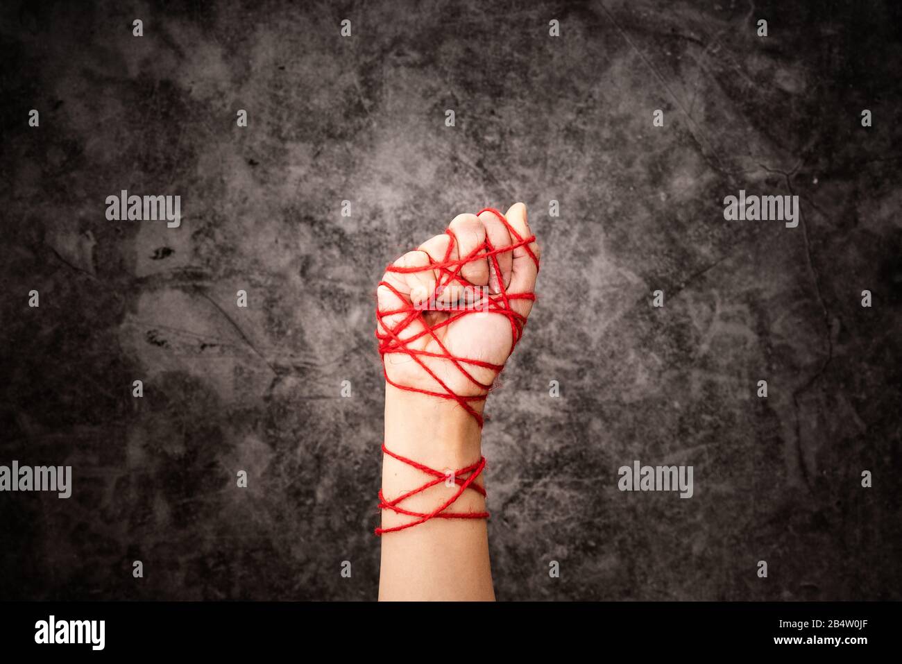 Le donne legate a mano con la corda, l'idea di libertà di espressione su sfondo oscuro grunge in chiave bassa. Concetto di giornata internazionale dei diritti umani. Foto Stock