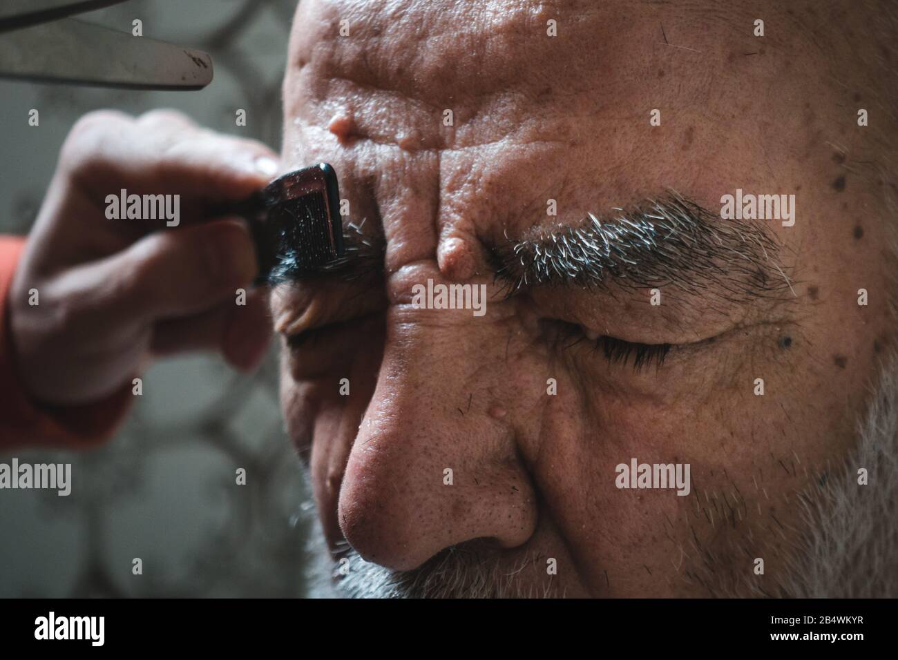 Uomo di 80 anni molto vecchio ottenere Il Suo sopracciglio Tagliato in bagno Foto Stock