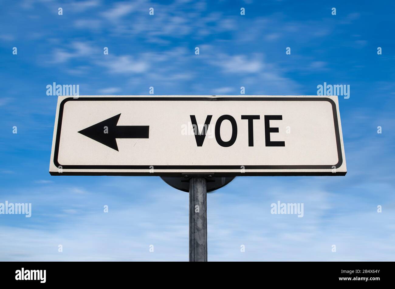 Segnale stradale di voto, freccia su sfondo blu cielo. Cartello stradale in bianco a senso unico con spazio per la copia. Freccia su un palo che punta in una direzione. Elezione. Foto Stock
