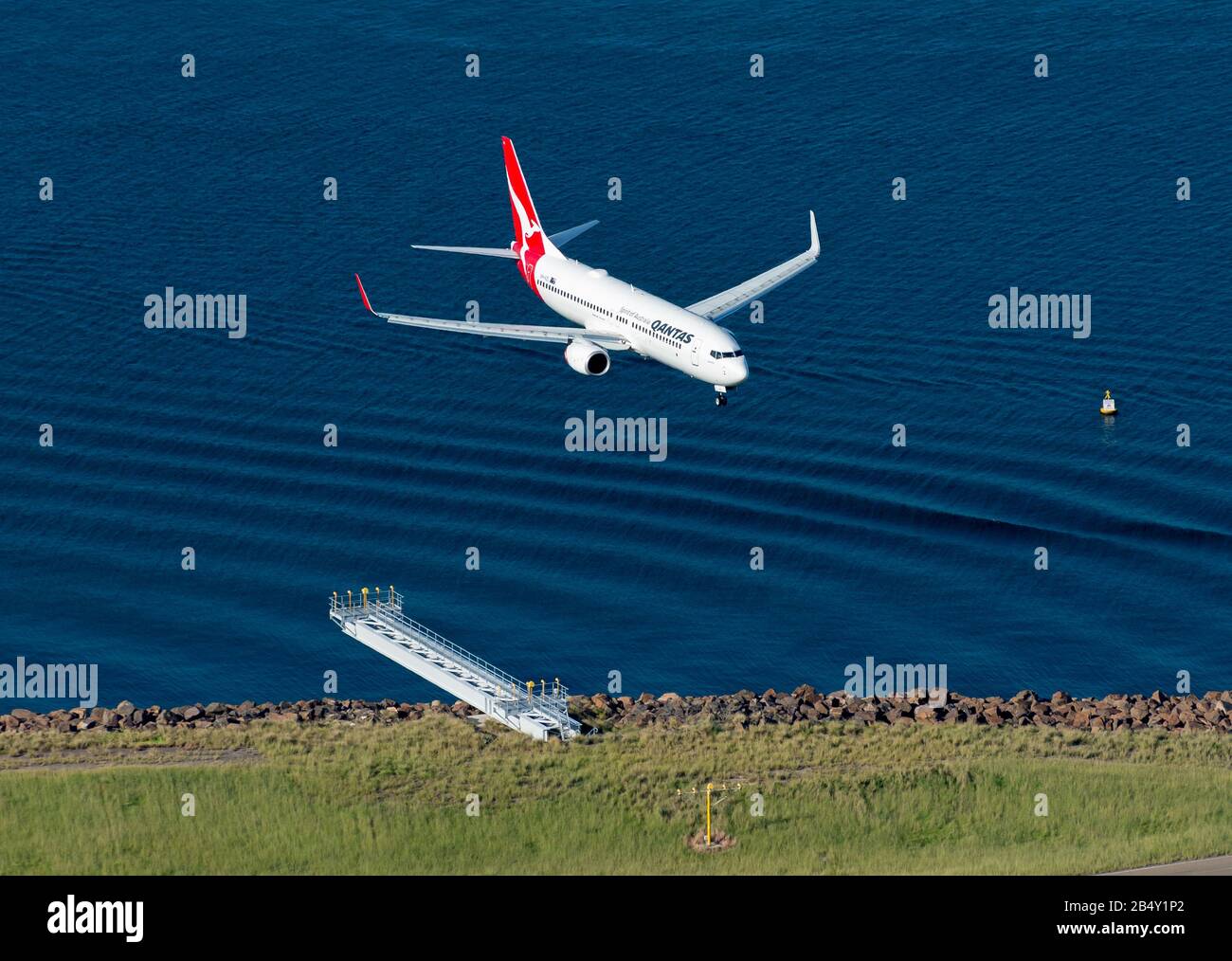 Veduta aerea del Boeing 737 della Qantas Airways sopra le acque della baia di Botany con le onde. Velivolo a corpo stretto con approccio finale. Volo nazionale da Melbourne. Foto Stock