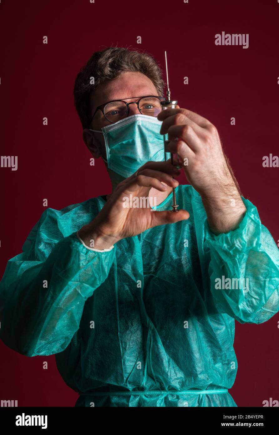 Il medico nella maschera medica effettua l'iniezione protettiva. Infermiere negli occhiali preparare la siringa. Medico che prepara la vaccinazione contro una pandemia e una stagione influenzale. Foto Stock