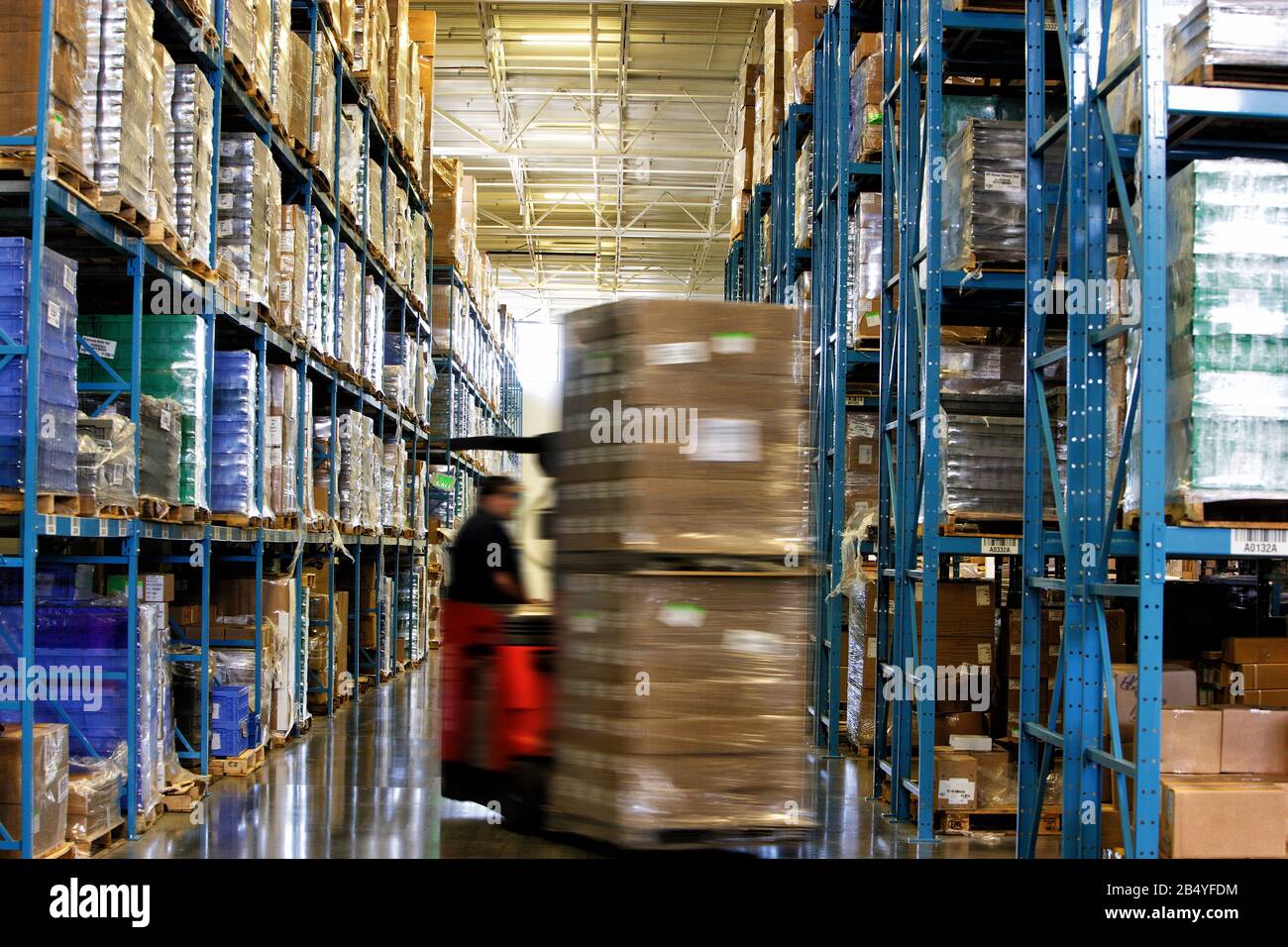 Un carrello elevatore a forca pallet di movimentazione delle merci in un grande magazzino. Foto Stock