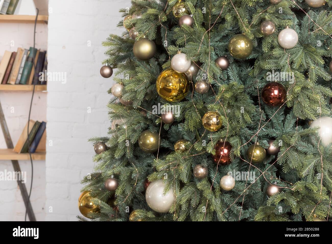 Albero di Natale con baubles bianco lucido, oro e bronzo in vita  room.branches di alberi di Natale con giocattoli marrone bronzo e ghirlanda  su un blurred Foto stock - Alamy