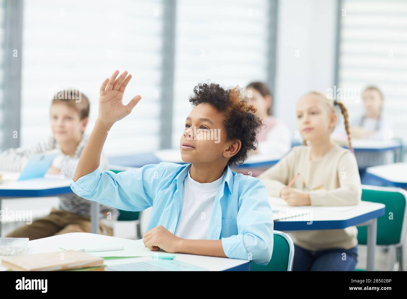 Ritratto orizzontale dello studente maschile intelligente della scuola  media alzando la mano per dare risposta in classe, copiare spazio Foto  stock - Alamy