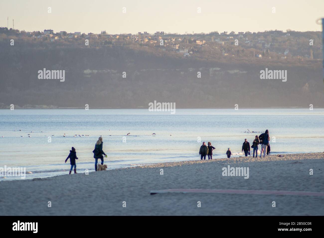 Persone che camminano sulla spiaggia, all'aperto, rilassarsi vicino all'acqua, al tramonto Foto Stock