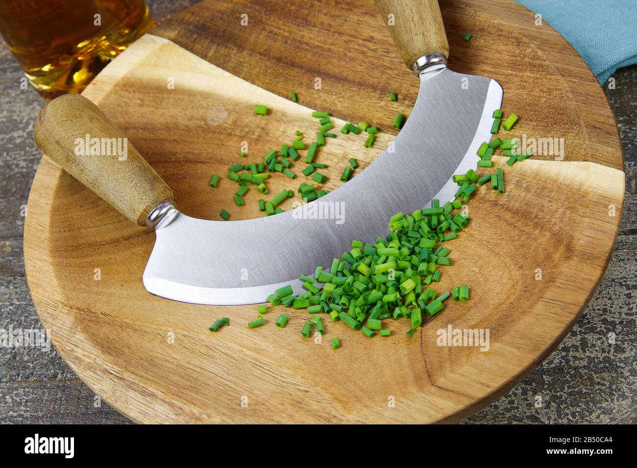Preparazione delle erbe per il pasto: Tagliere in legno marrone isolato con lo chef´s coltello da taglio, erba cipollina tritata Foto Stock
