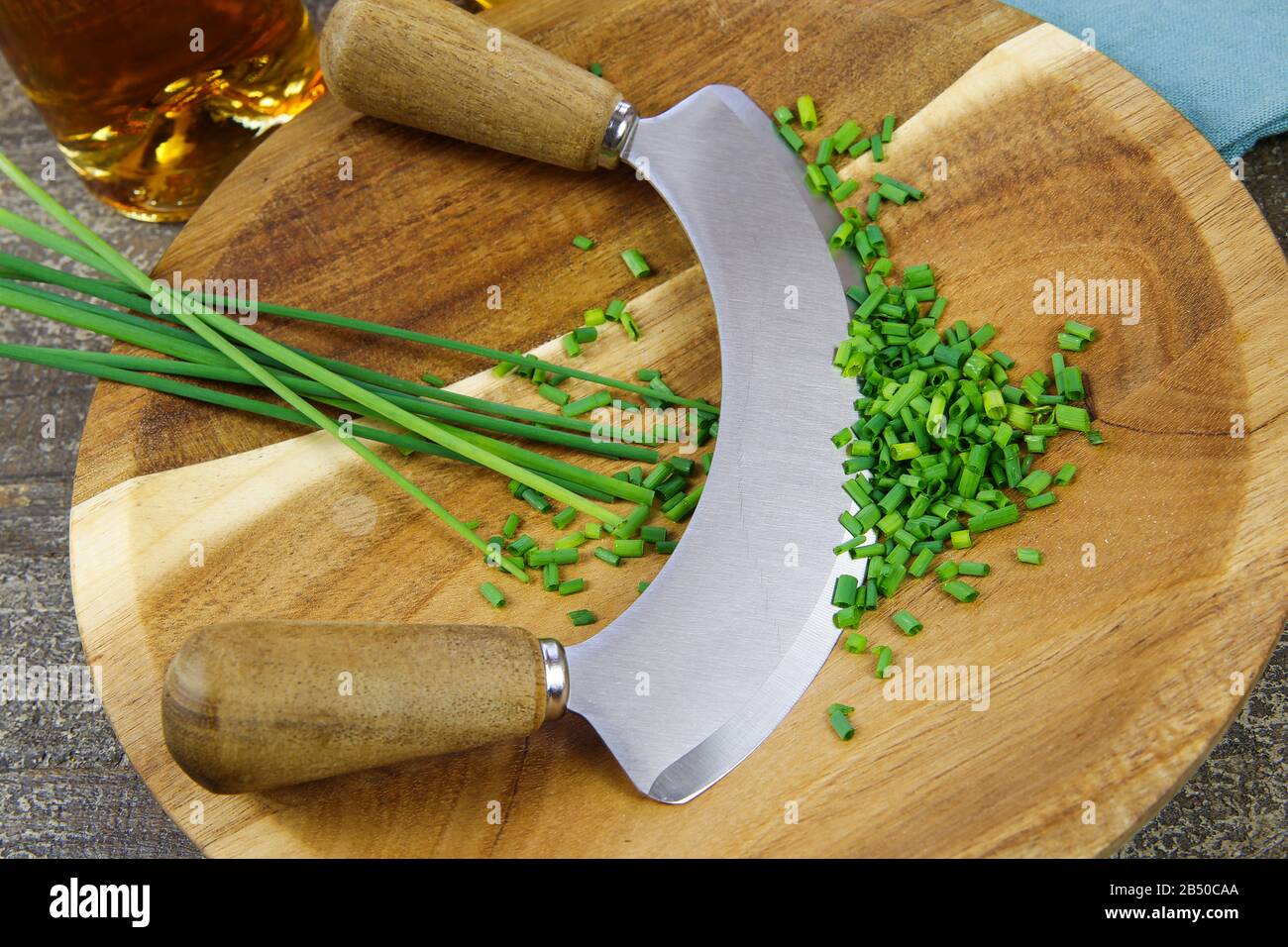 Preparazione delle erbe per il pasto: Tagliere in legno marrone isolato con lo chef´s coltello da taglio, erba cipollina tritata Foto Stock