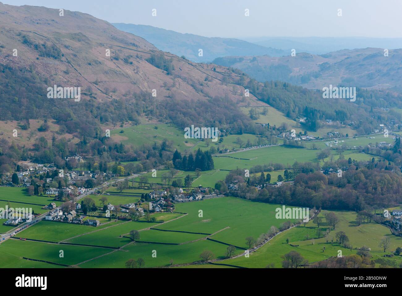 Grasmere villaggio, Fairfield ferro di cavallo e Loughrigg cadde sullo sfondo, visto dalla cima di Helm Crag, Grasmere, Lake District, Cumbria, Regno Unito Foto Stock