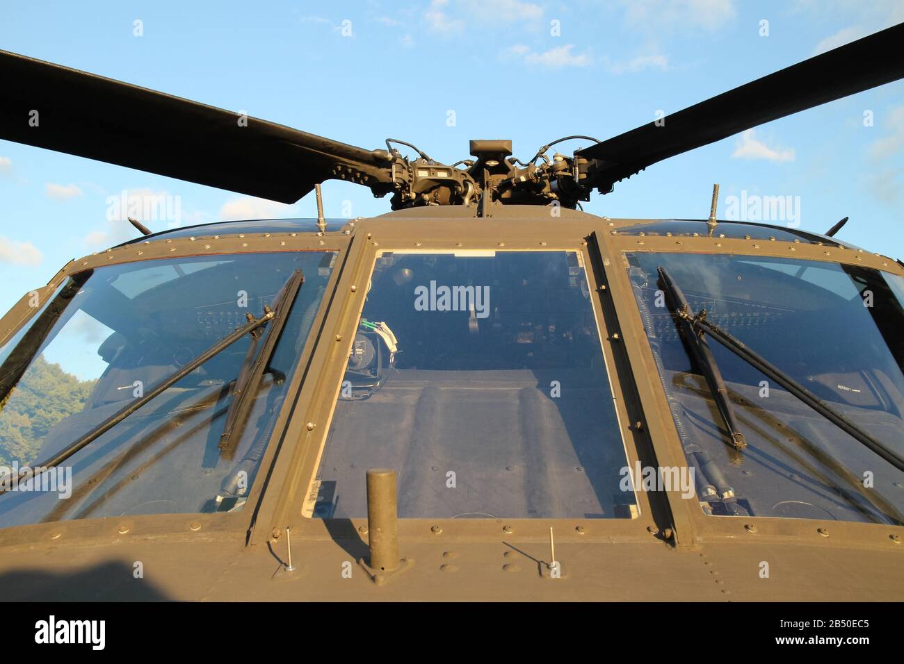 vista frontale ravvicinata di un parabrezza di un elicottero militare color olivo contro un cielo blu Foto Stock