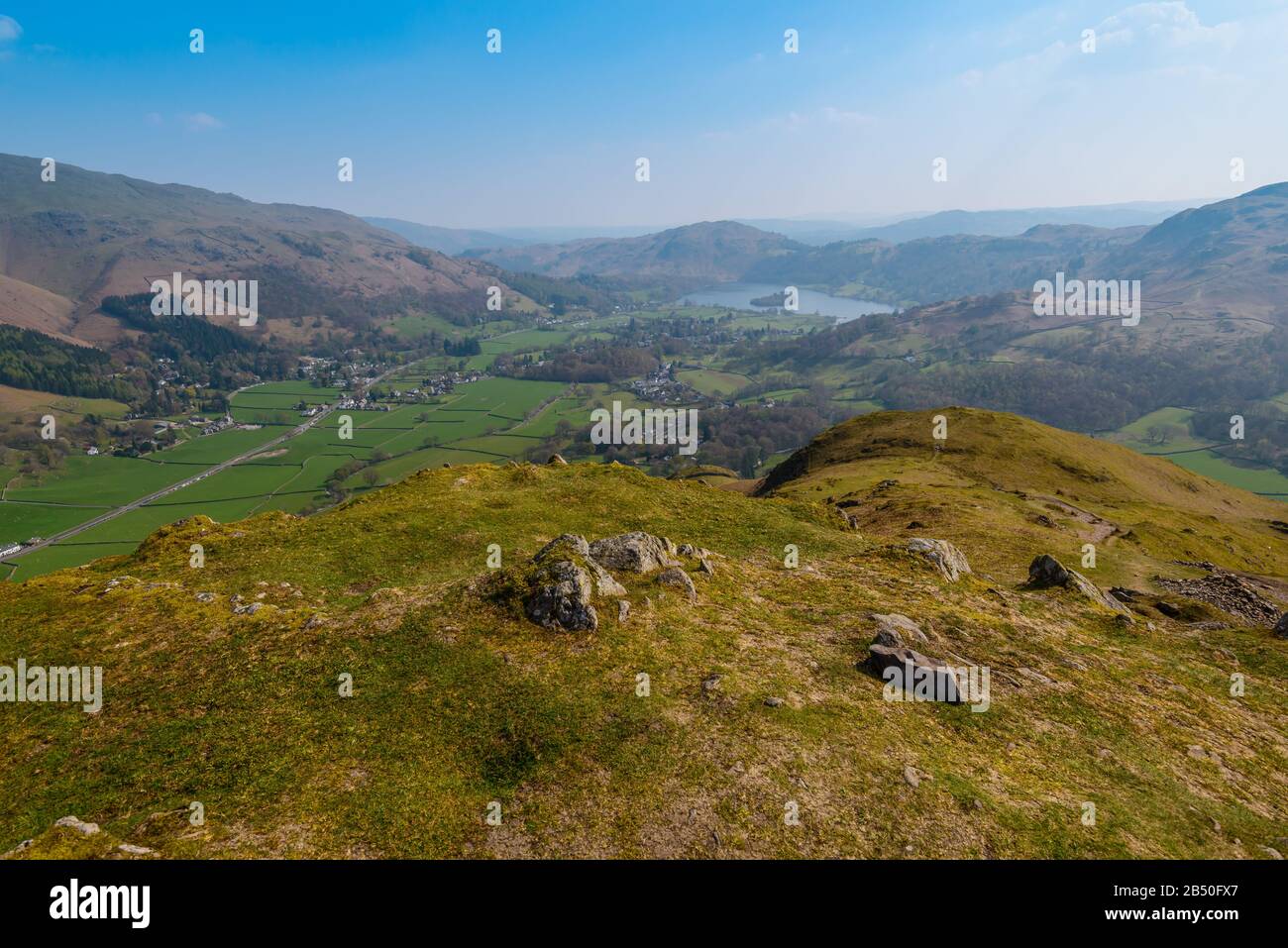 Grasmere villaggio e lago, Fairfield ferro di cavallo e Loughrigg cadde sullo sfondo, visto dalla cima di Helm Crag, Grasmere, Lake District, UK Foto Stock