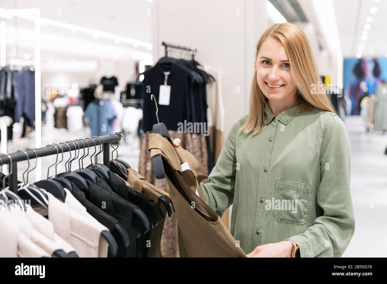 felice giovane donna sceglie i vestiti in un centro commerciale Foto Stock