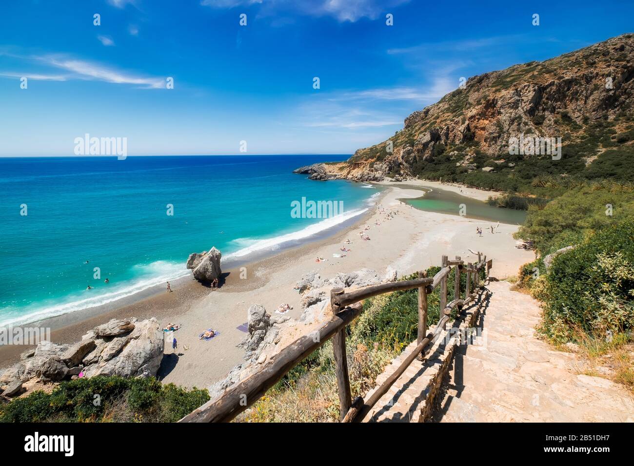 Incredibile spiaggia Preveli con acque turchesi e colline rocciose. Persone che nuotano in acque azzurre e che nuotano sulla sabbia. I turisti che si rilassano a Creta al sole Foto Stock