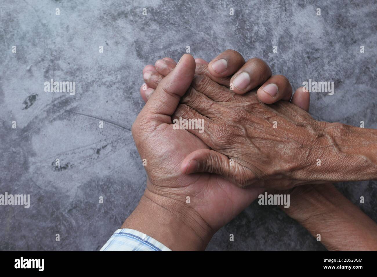 Giovane uomo che tiene le mani con una signora superiore. Foto Stock