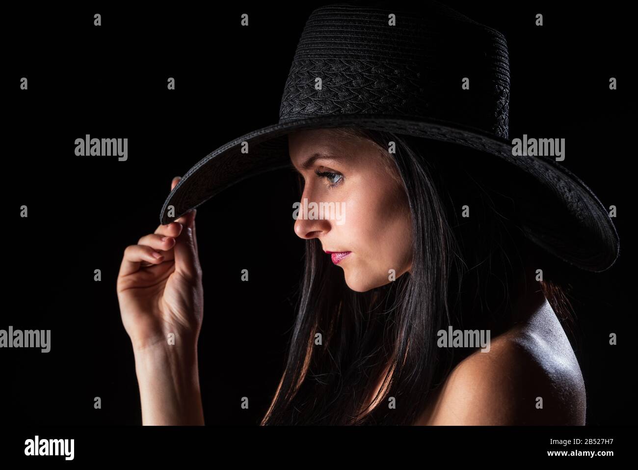 Giovane donna nuda con make up. Modello con cappello. Nudo ragazza bellezza ritratto su sfondo nero. Foto Stock
