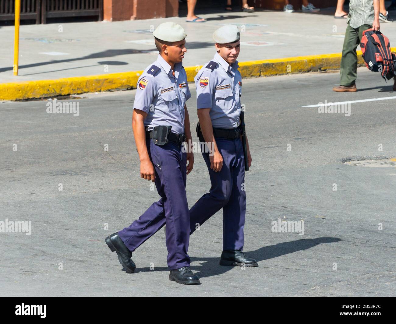 Due giovani poliziotti maschili in uniforme blu camminano a l'Avana, nel centro di Cuba. Poliziotti che indossano beretta. Autorità cubane. Foto Stock